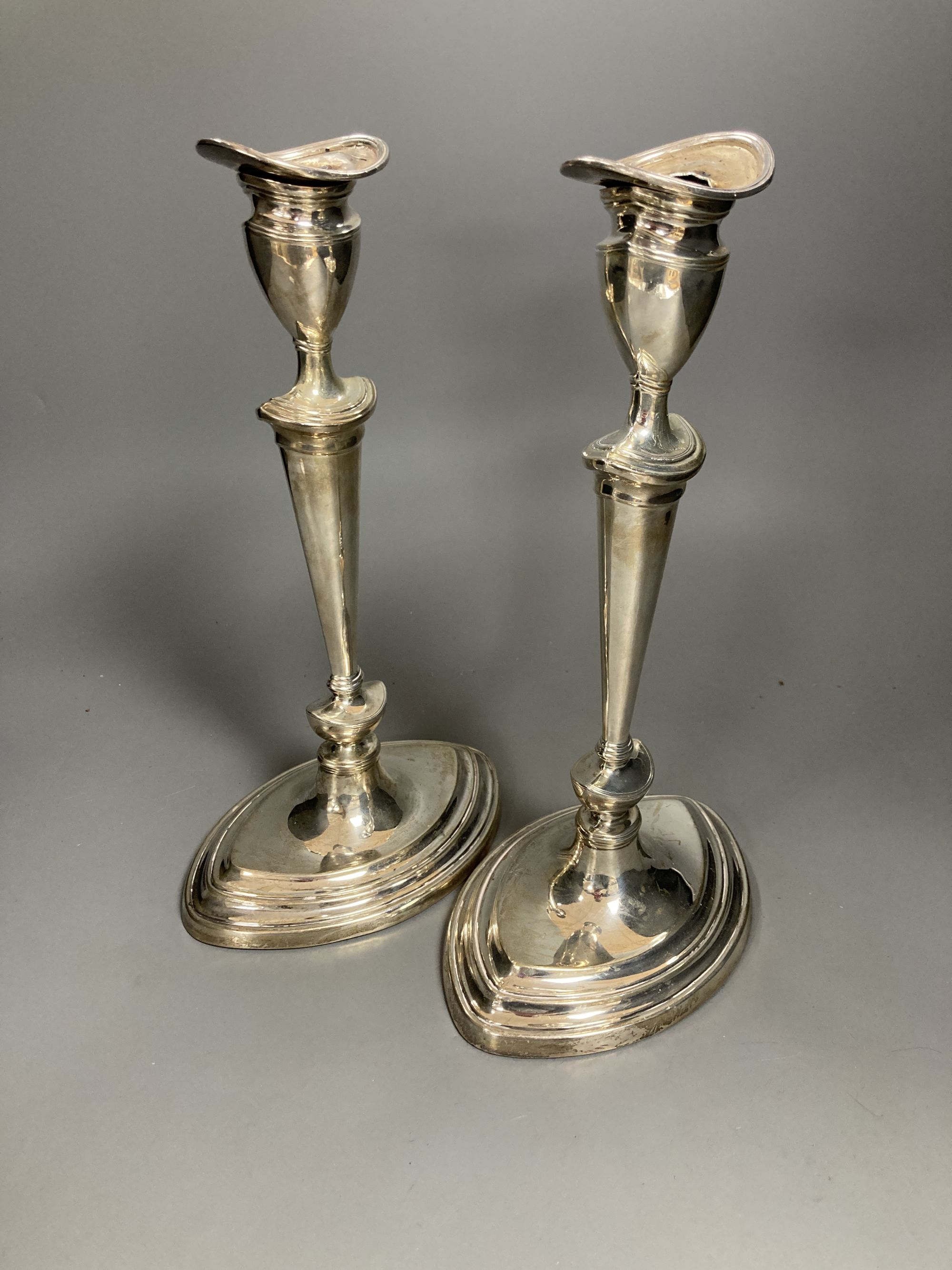 A pair of Edwardian silver oval candlesticks, by Goldsmiths & Silversmiths Co Ltd, London, 1903, loaded, 30.3cm, (sconces a.f. and stuck in situ).